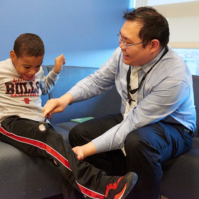 Chalongchai Phitsanuwong, MD checks Patient William Sterling's reflexes