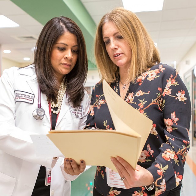 Ami Desai, MD, MSCE, looks at files with Melody Perpich, MS, CGC