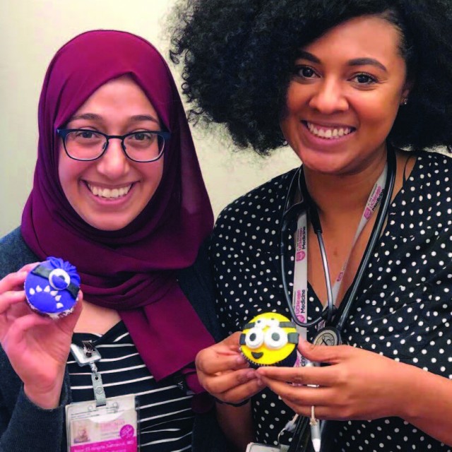 Residents Alanna Burnett, MD (Med/Peds) and Nour Sahraoui, MD holding themed cartoon cupcakes