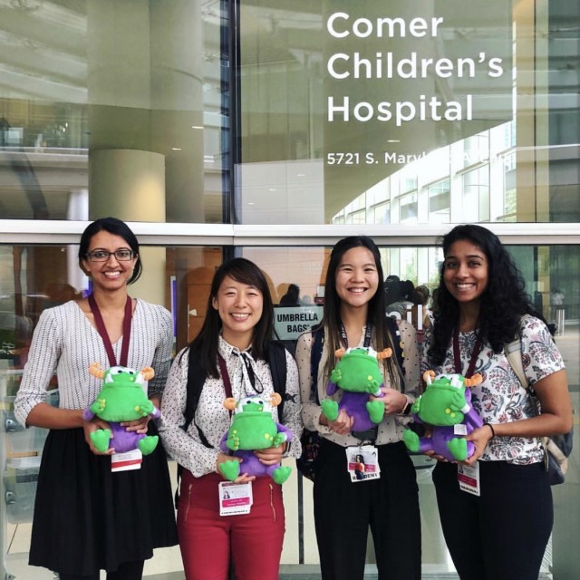 Four residents holding plush Remoc toys outside of Comer Children&#039;s Hospital