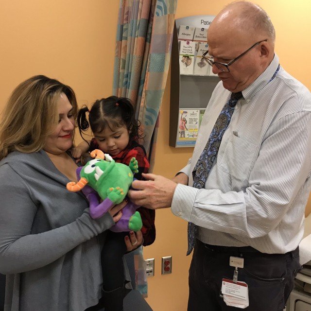 Michael Msall, MD giving a patient and her mother a Remoc plush toy