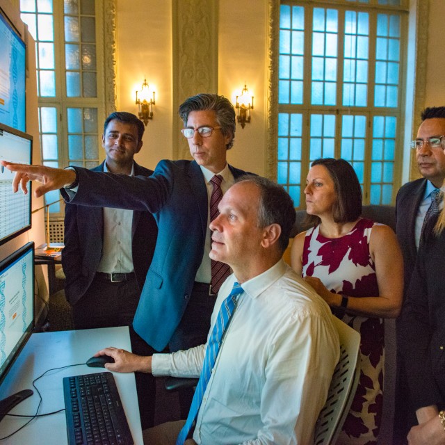 People in professional clothing gathered around a screen